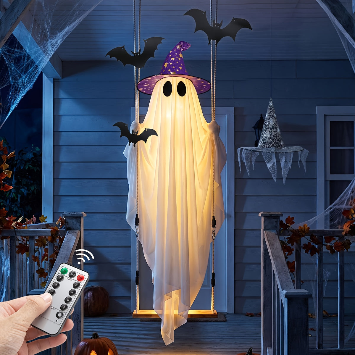 Swing ghost Halloween decoration hanging from a tree branch in a front yard at night