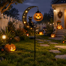 Black metal crescent cat garden stake with a hanging pumpkin planted in a lawn