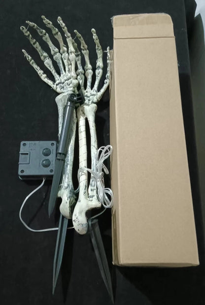 Skeleton hand solar lights displayed in a garden bed