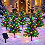 Row of mini solar Christmas tree stake lights glowing multicolor along a garden path