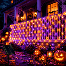 Orange and purple LED solar net lights draped over outdoor bushes for Halloween - view 1