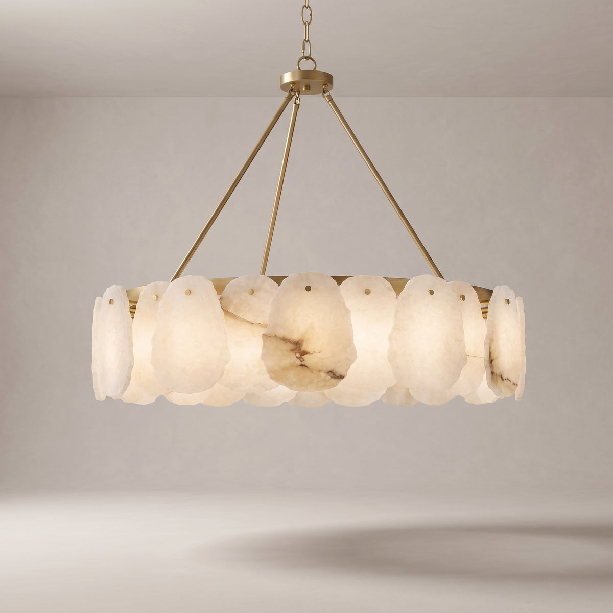 Alabaster chandelier with a brushed gold brass frame on a grey studio background