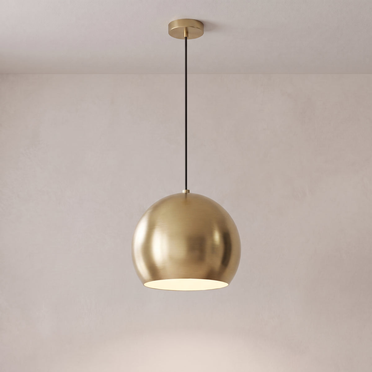 Vesper brass globe pendant light in brushed gold on a grey studio background