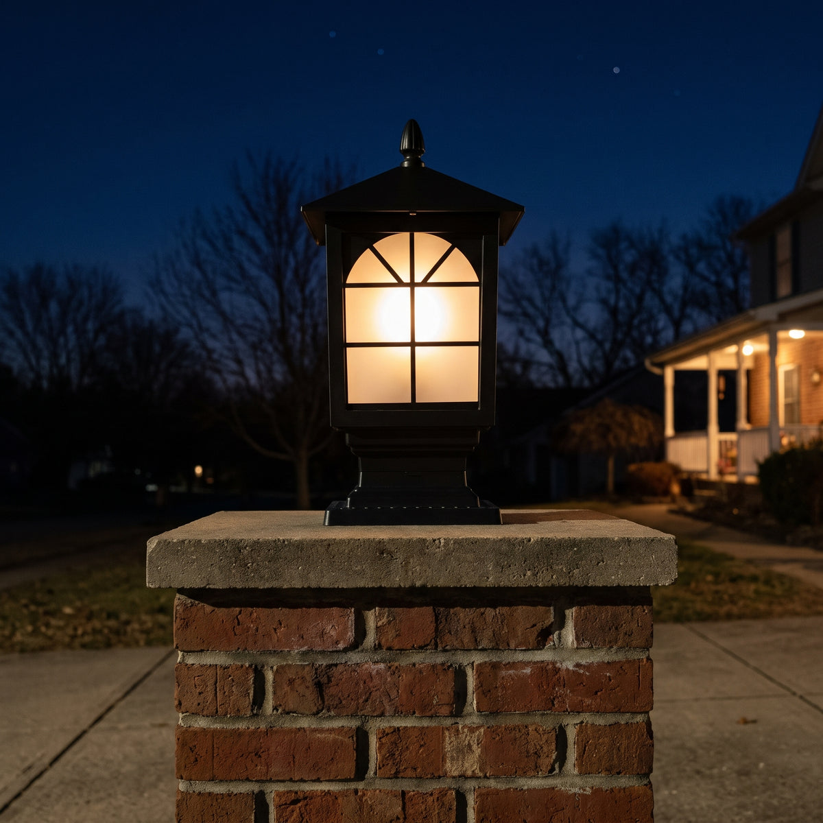 Birchwood post light glowing warm on a brick driveway pillar at night