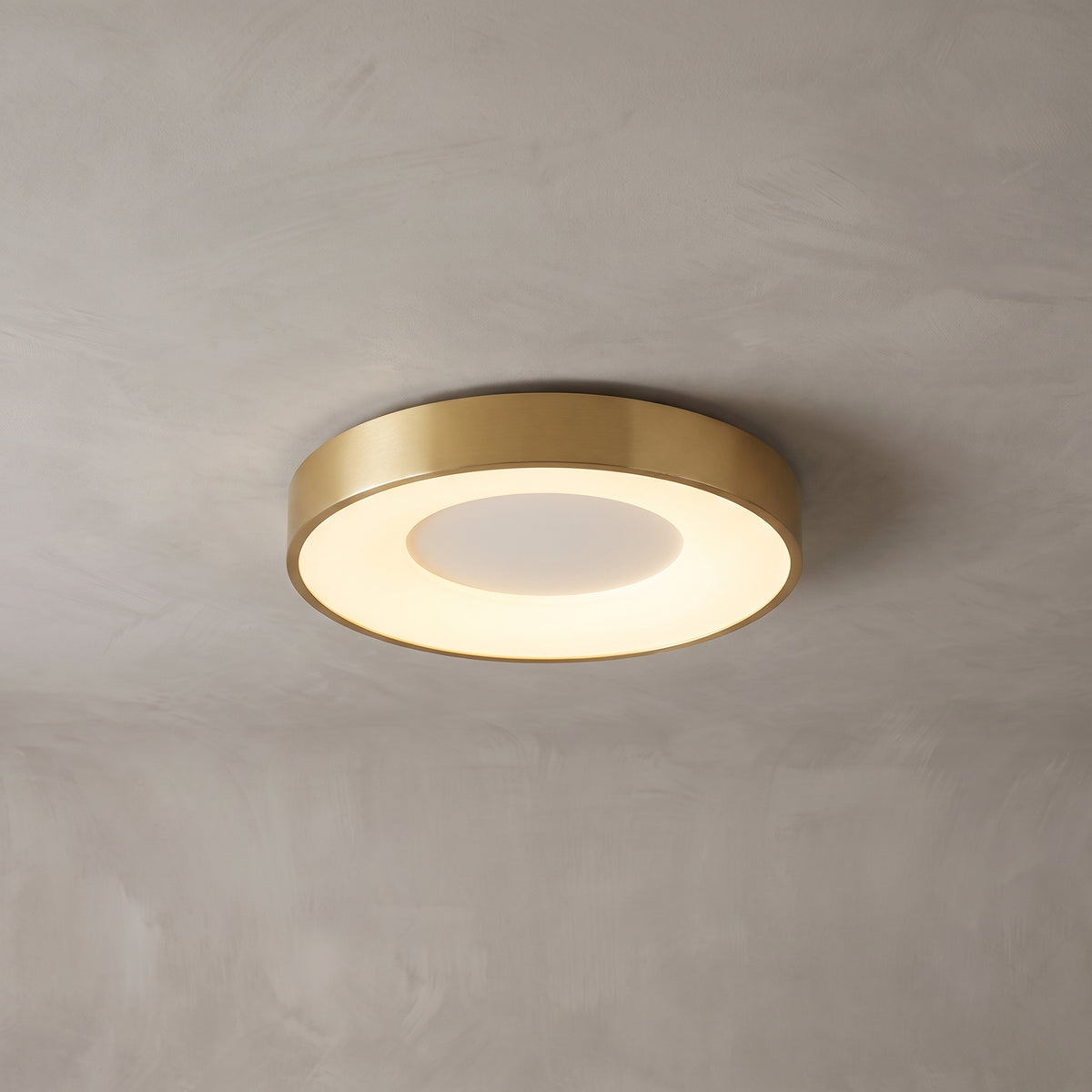 Alaric round flush mount ceiling light in brushed gold on a grey ceiling