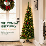 Unlit green PVC Christmas tree beside a fireplace
