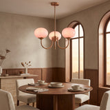 Cloudlet glass chandelier with pink hand-sprayed shades above a round walnut dining table