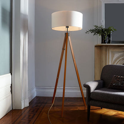 Tripod floor lamp glowing warm white beside a reading chair
