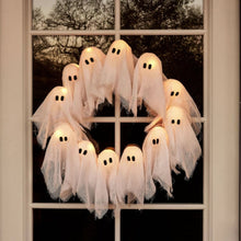 Illuminated ghost Halloween wreath hanging on a front door