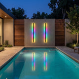 Haylen RGB wall light in color changing mode beside a pool at night