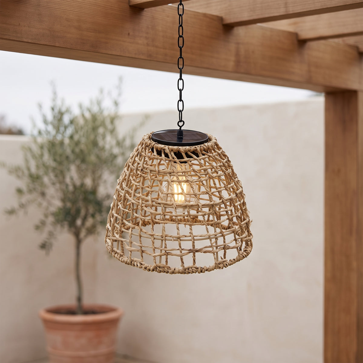 Havana rattan solar pendant lantern glowing under a pergola