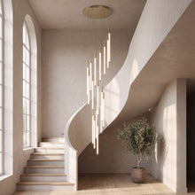 Gold cascading LED tube chandelier in a curved stairwell