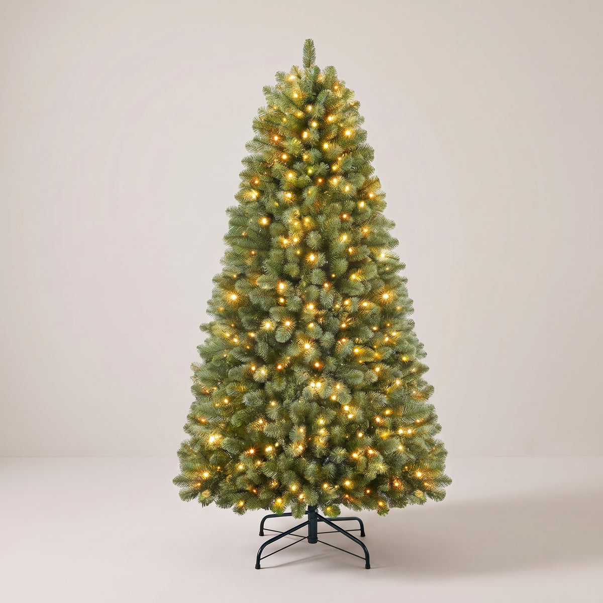 Pre-lit Christmas tree with warm white lights on, studio photo