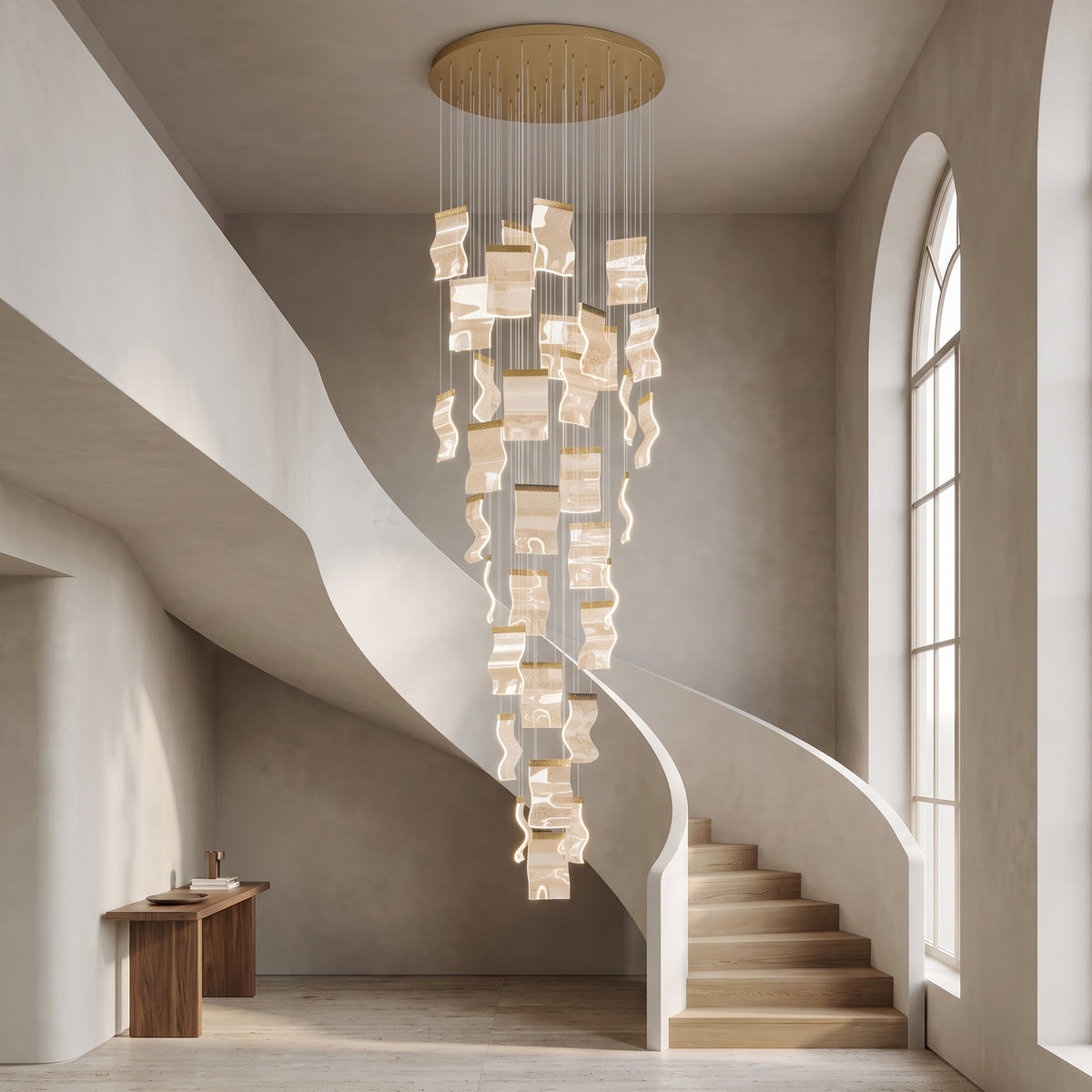 Nyra cascading chandelier in metallic gold in a double-height stairwell