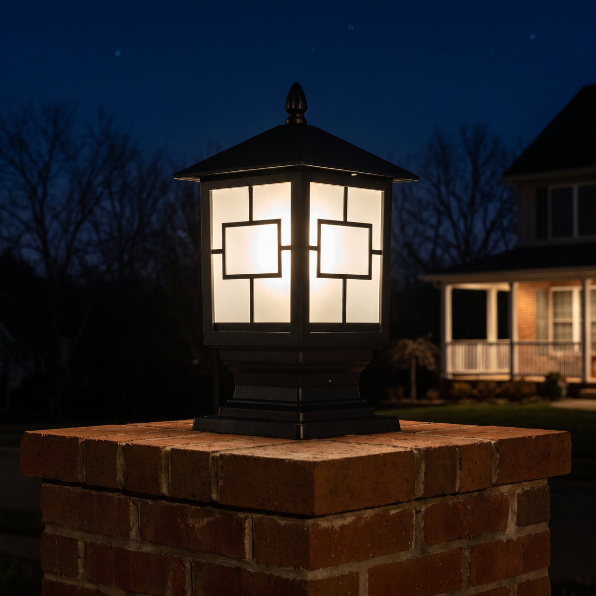 Oakmont post light glowing warm on a brick driveway pillar at night