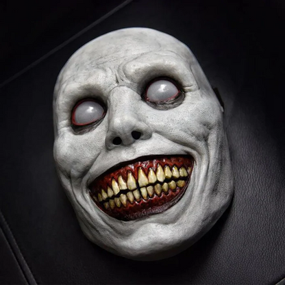 Creepy smiling costume mask in soft latex, with a wide grin, yellow teeth and blank white eyes