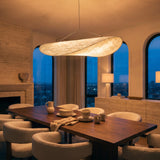 Kinu silk sail pendant light above a walnut dining table in an evening city apartment