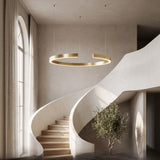 Gold-plated ring chandelier suspended in a curved stairwell