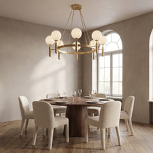 Solenne brass chandelier, round base, above a round walnut dining table
